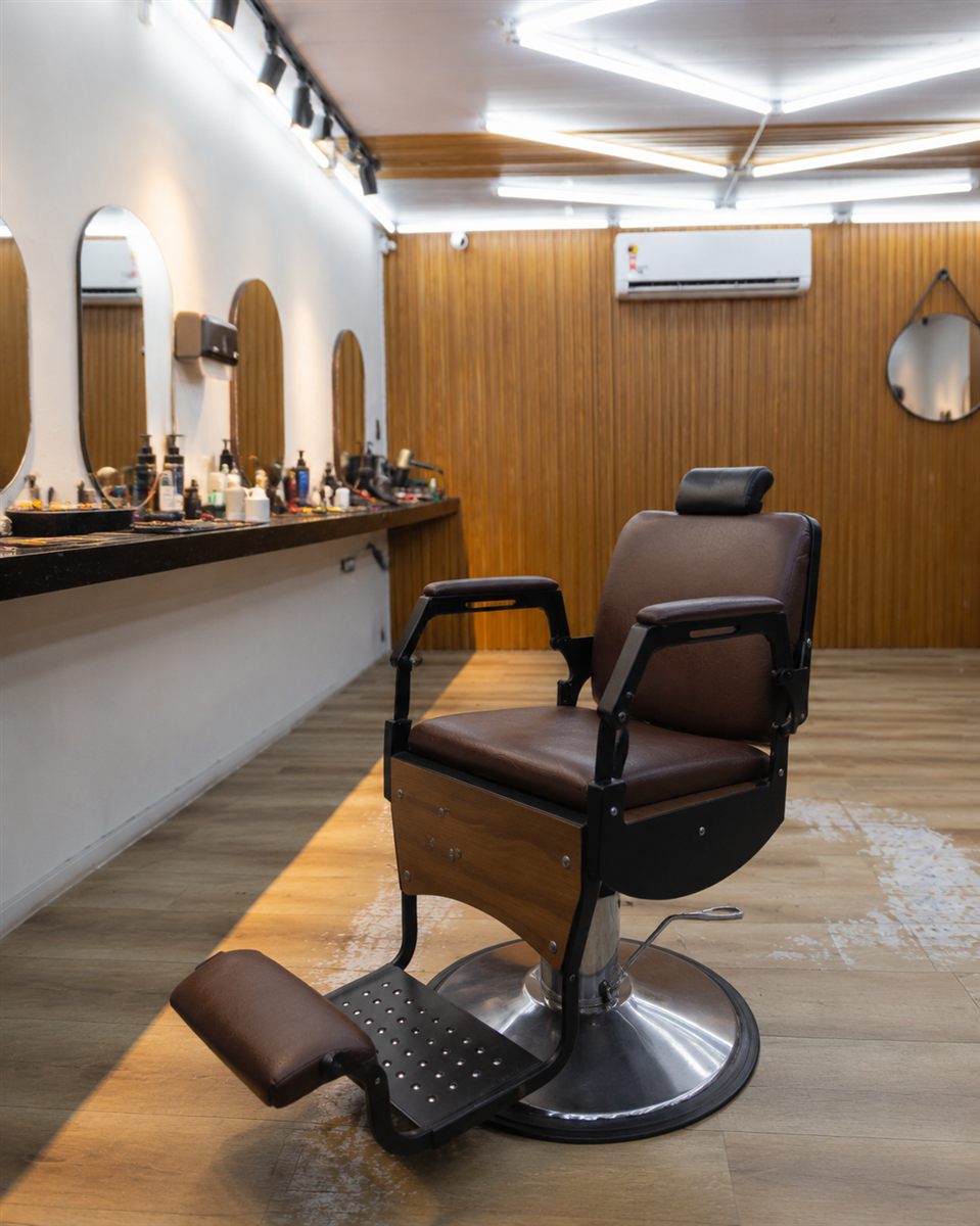 Cadeira de barbeiro vazia em barbearia parceira, ambiente de espera antes do diagnóstico